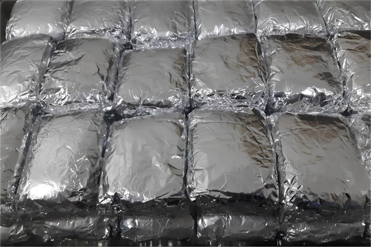 Bolo gelado embrulhado no papel alumínio com 2 camadas de recheio e cobertura de coco ralado