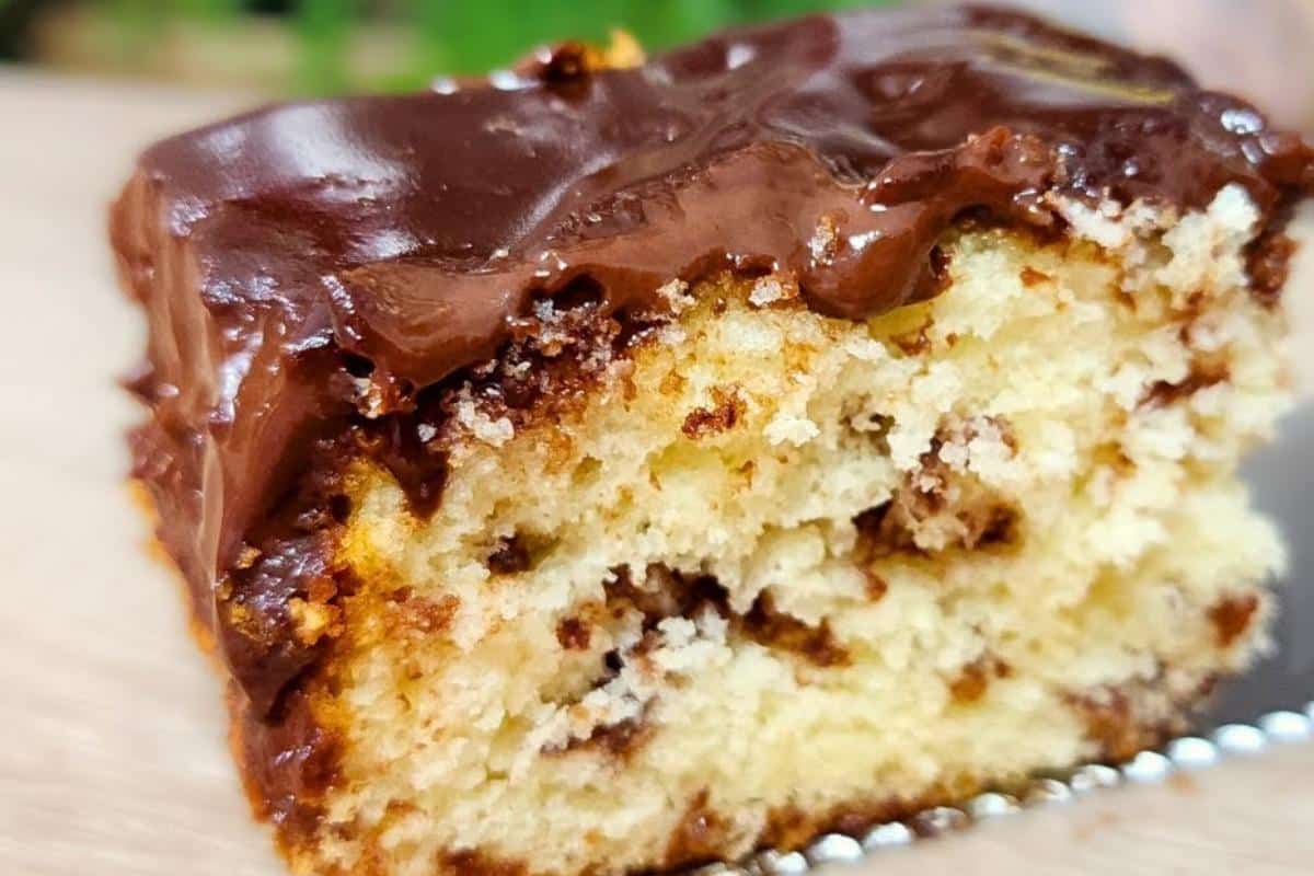Bolo amanteigado de coco fofinho com cobertura de chocolate que é espetacular